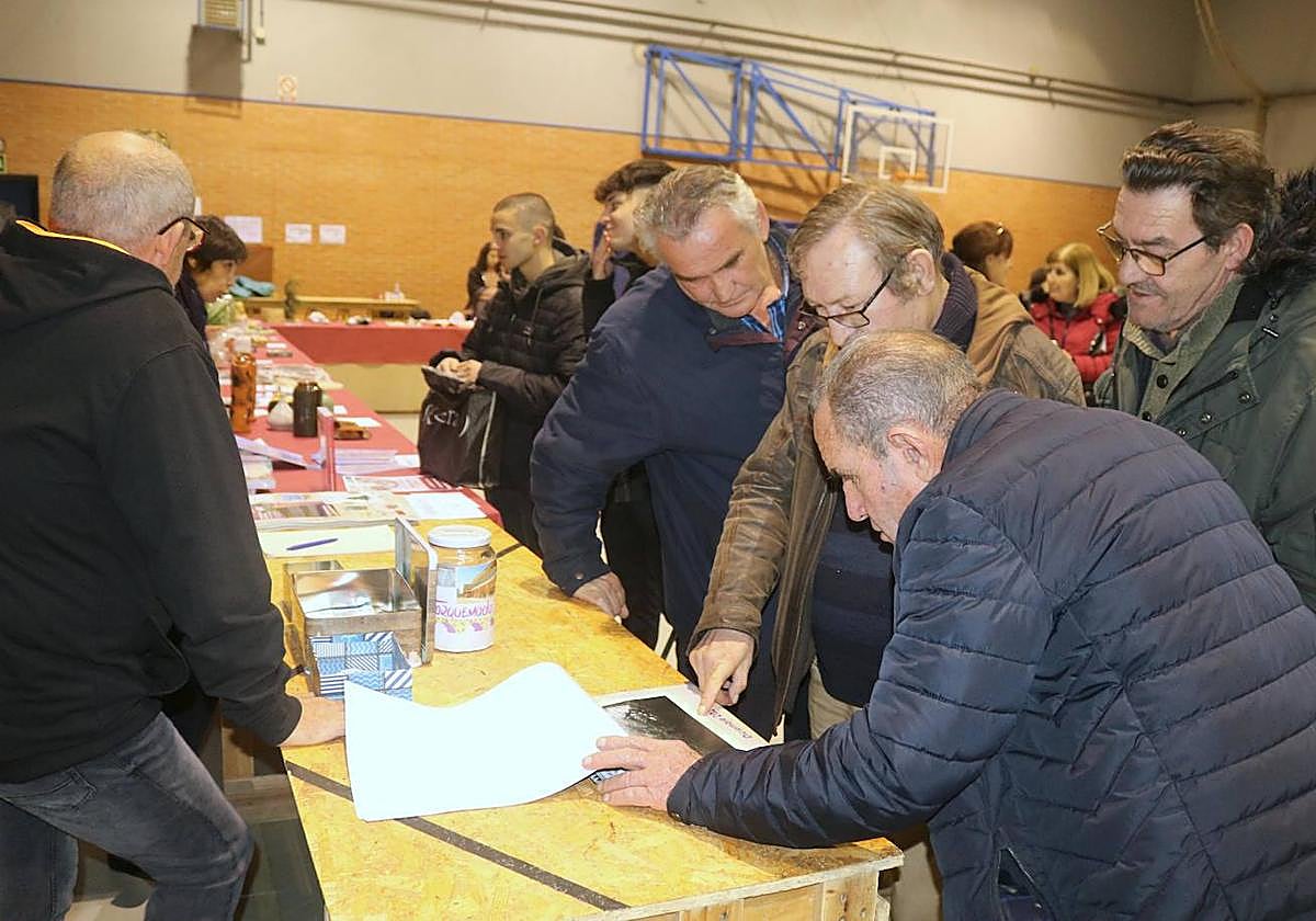 Varios vecinos observan el nuevo calendario solidario de Torquemada.