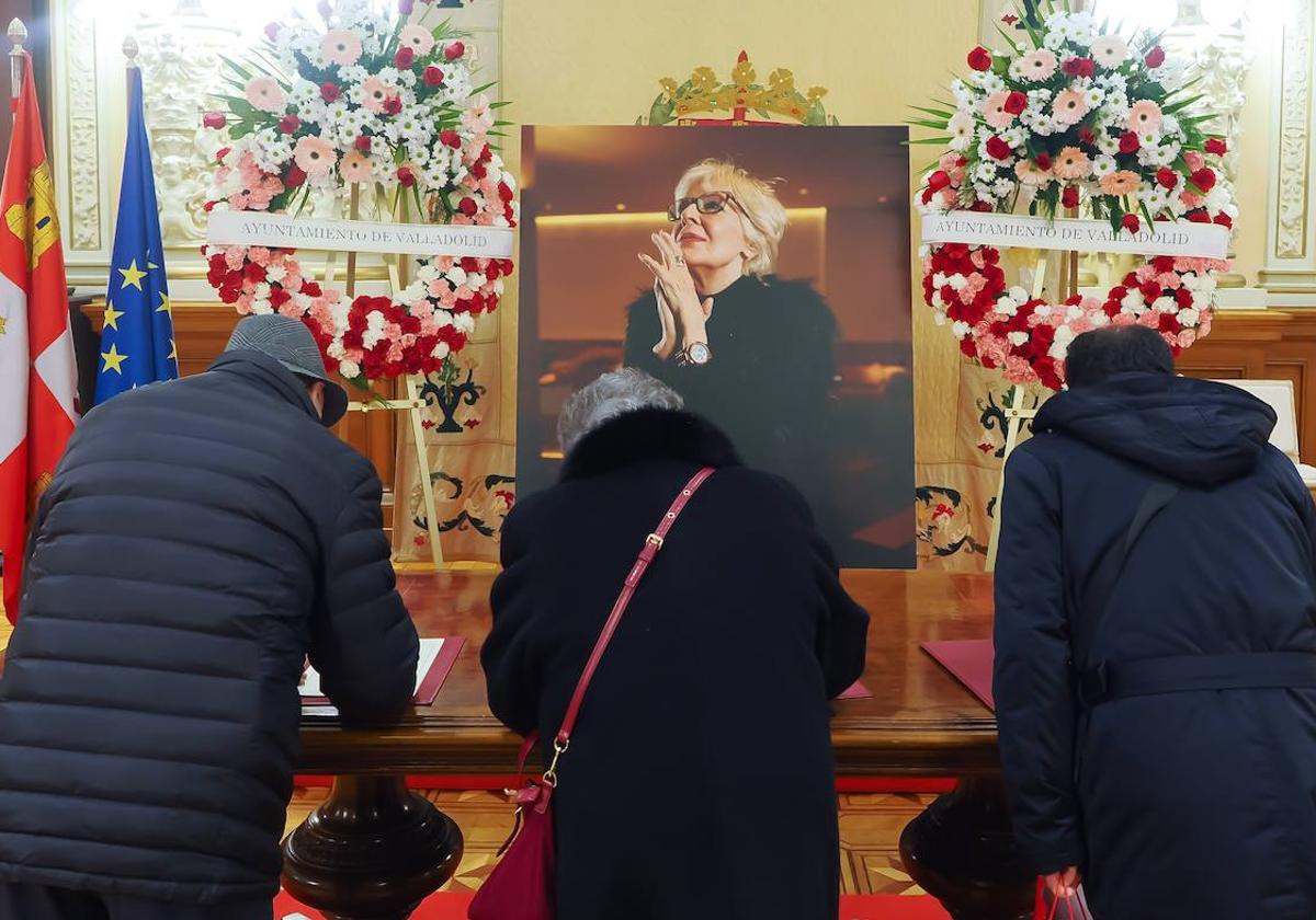 Tres personas firman en el libro de condolencias en el salón de recepciones del Ayuntamiento.