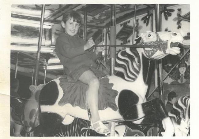 Pilar Ortega, durante su infancia, montada en uno de los caballitos de madera tallada del carruasel centenario.