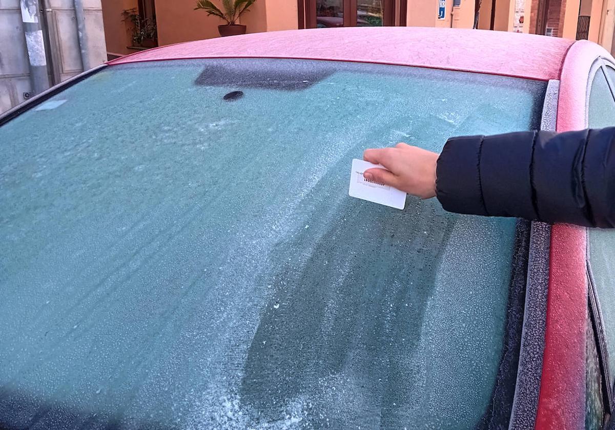 Una persona quita el hielo de la luna de su coche en Segovia.