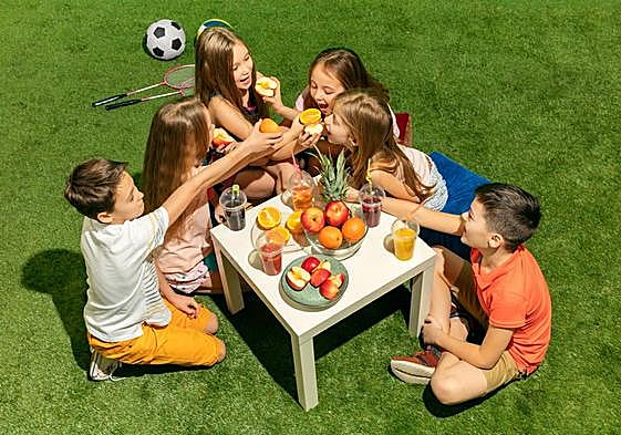 Niños comiendo fruta después de practicar deporte.