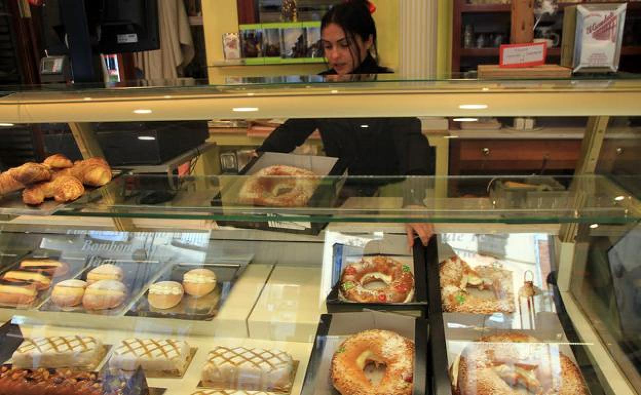 Una trabajadora coloca roscones en el mostrador de una pastelería. 