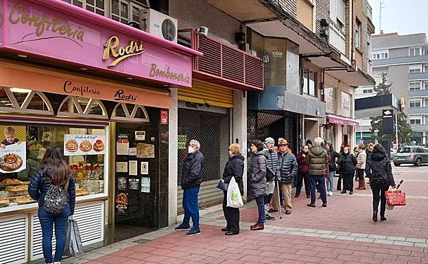 Cola de clientes para comprar un roscón en una pastelería. .