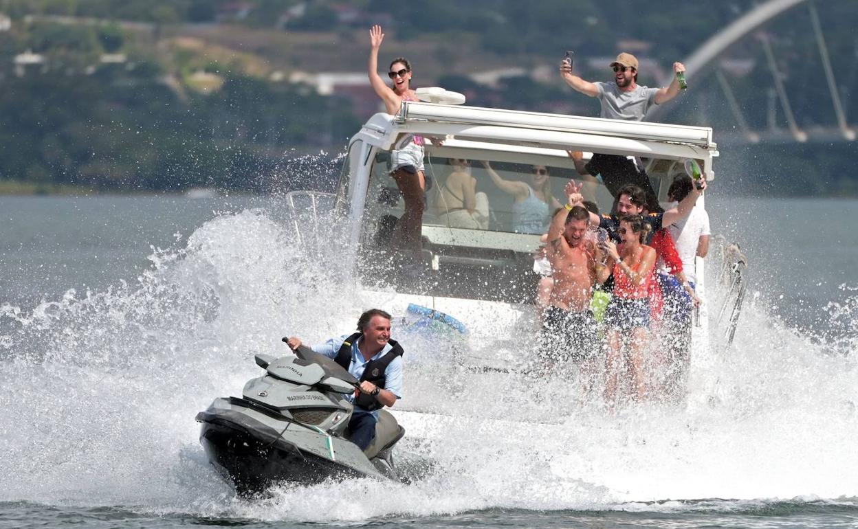 En esta imagen del 15 de mayo de 2022, el expresidente brasileño Jair Bolsonaro monta en una moto acuática mientras sus partidarios participan en un paseo en barco en el lago Paranoa en Brasilia.