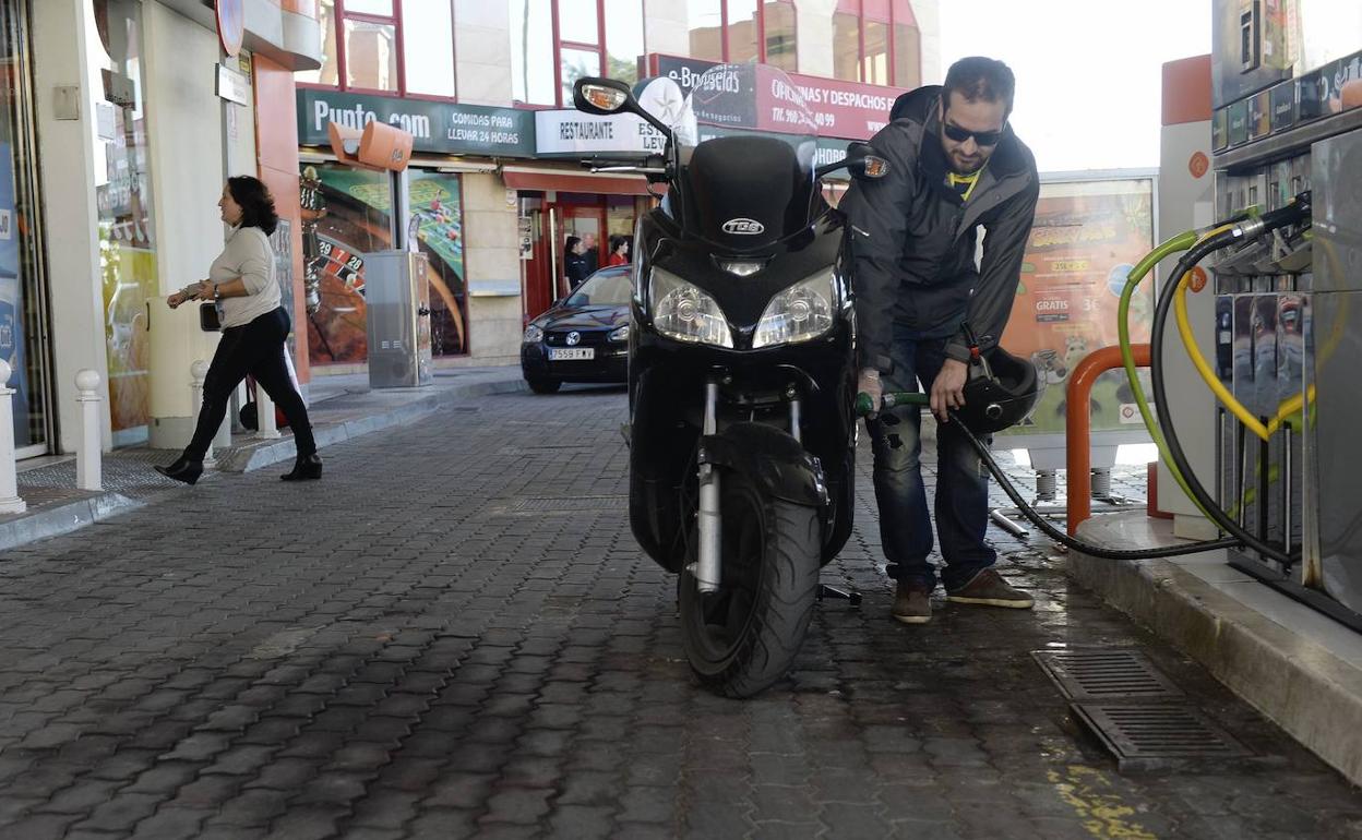 Un motorista llena el depósito de su moto en un surtidor. 