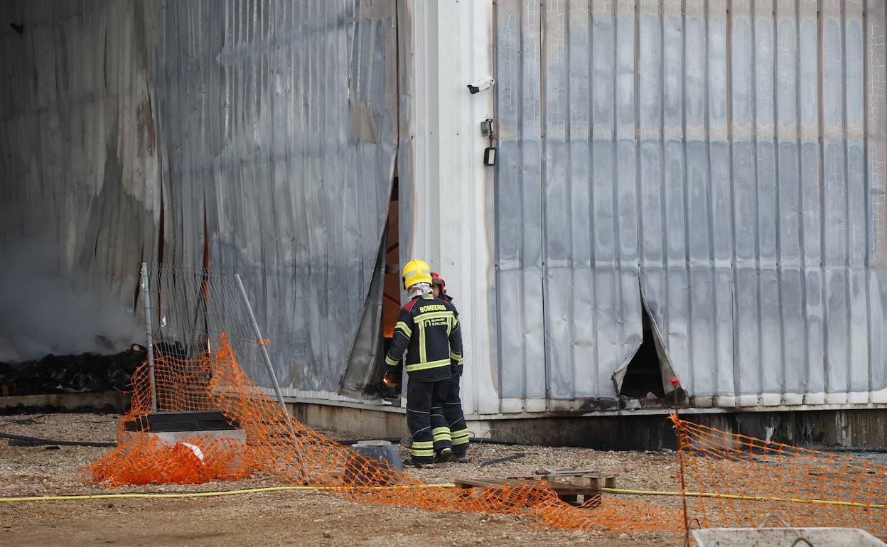 Los bomberos trabajan en la fábrica arrasada por el incendio. 