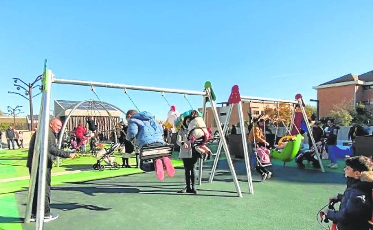 Niños y niñas juegan en los columpios de un parque. 