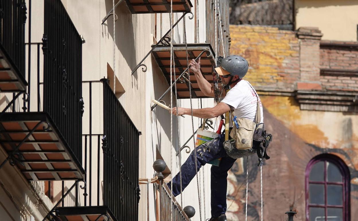 Un trabajador pinta la fachada de un edificio. 