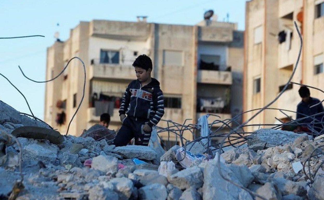 Niño sobre ruinas tras el terremoto en Siria.