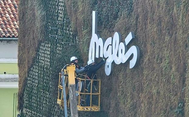 Los operarios retiran el letrero de El Corte Inglés de la fachada del edificio de Constitución. 