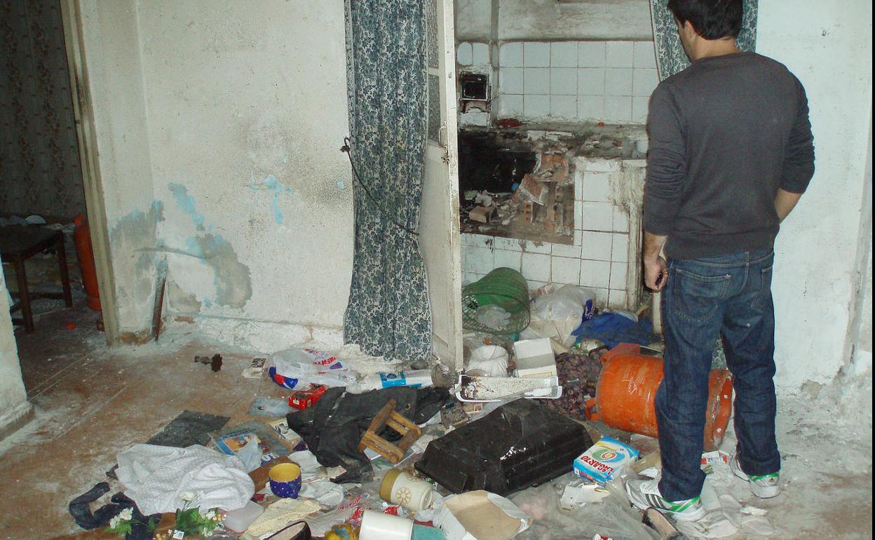 Un hombre observa el interior de una casa con mucha basura. 