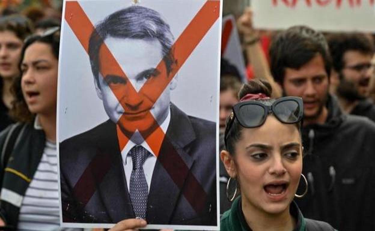 Una mujer exhibe una pancarta en contra del primer ministro griego, Kyriakos Mitsotakis, durante una protesta en Atenas.