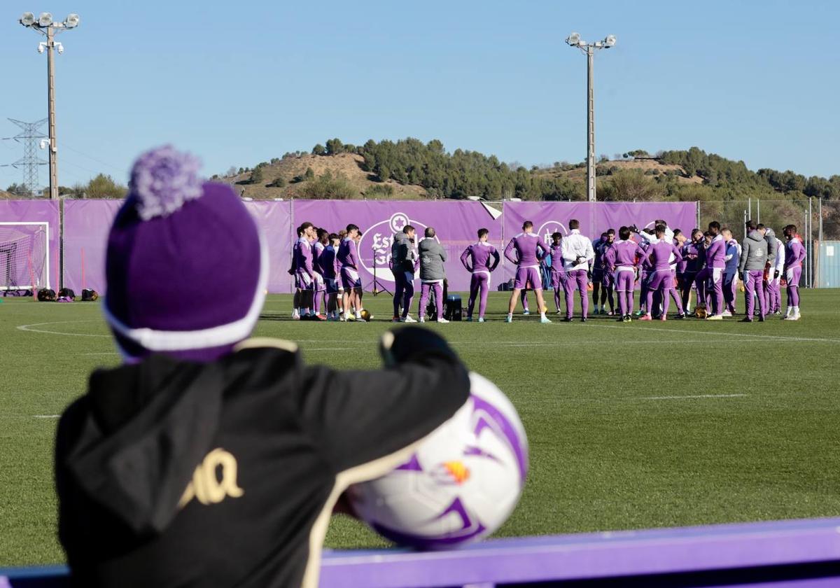 Un niño observa el corro de los jugadores antes de iniciar el entrenamiento del Real Valladolid en los Anexos.