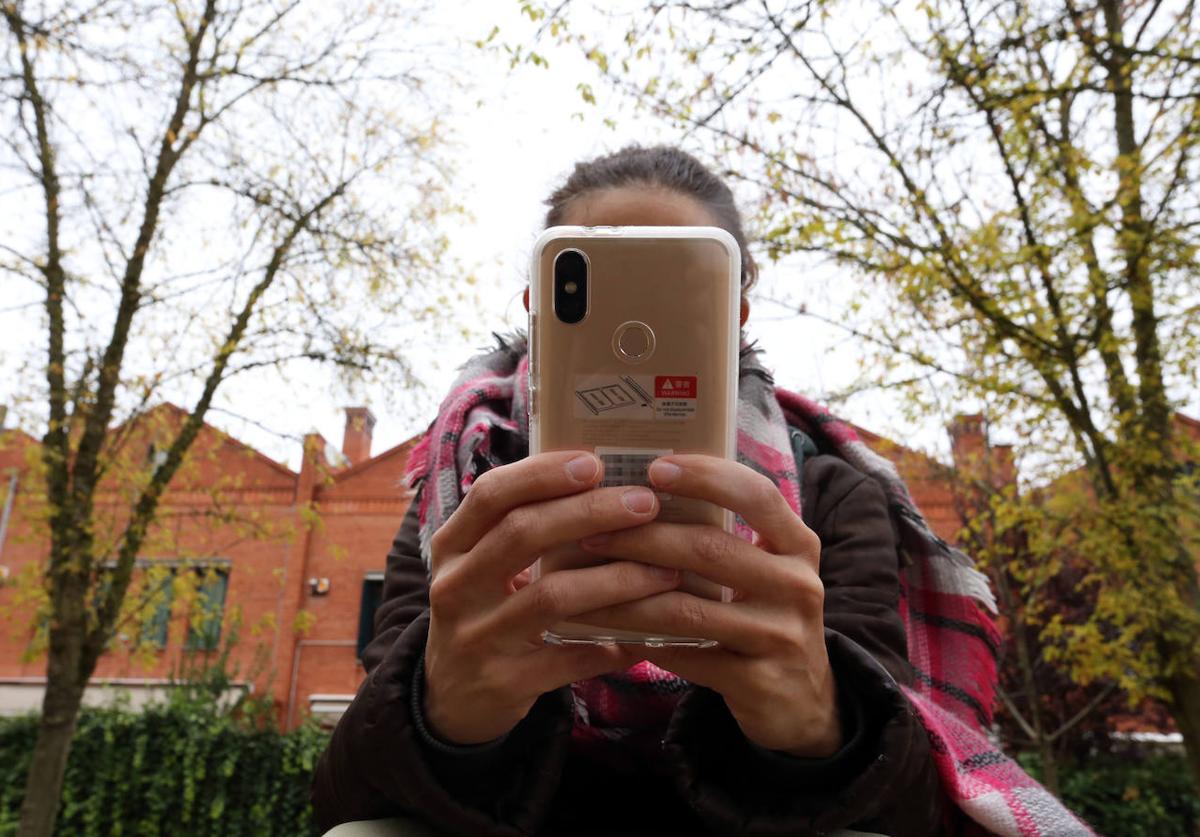 Una joven utiliza su teléfono móvil junto a un instituto de Valladolid capital.