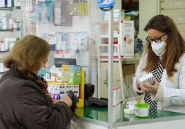 Una mujer adquiere medicamentos en una farmacia.