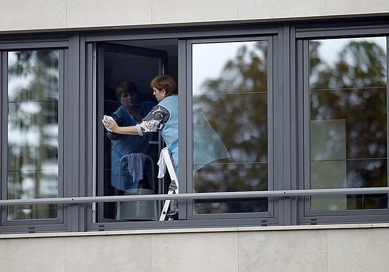 Una trabajadora del servicio de limpieza realiza su labor en unas ventanas, en una imagen de archivo.