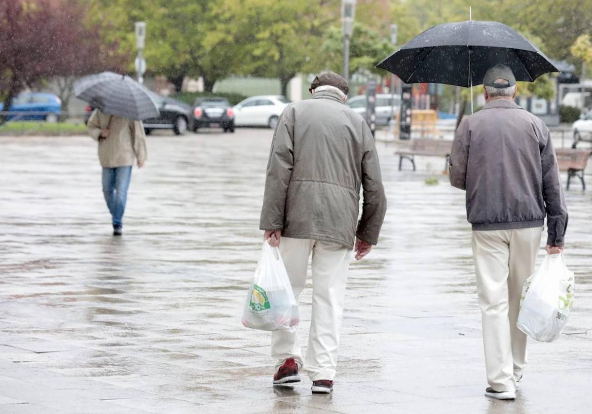 Dos hombres se protegen de la lluvia en Valladolid, en una imagen de archivo.