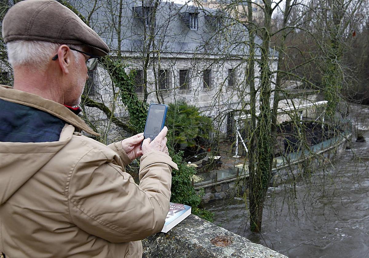 Un hombre saca una foto a la crecida del Eresma.