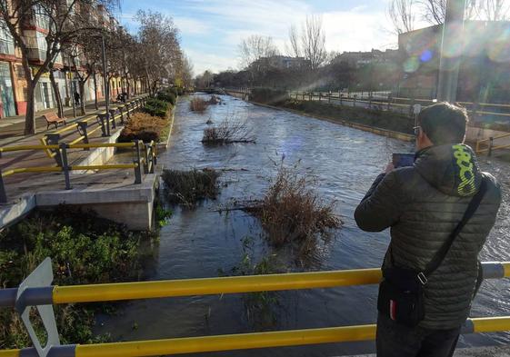 Un viandante saca fotos del Esgueva en la mañana de este jueves.