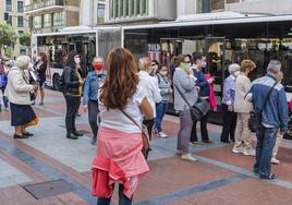 Un grupo de personas espera el autobús en la parada de la plaza de España.