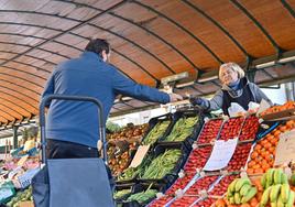 Un cliente paga su compra a una frutera del mercado.