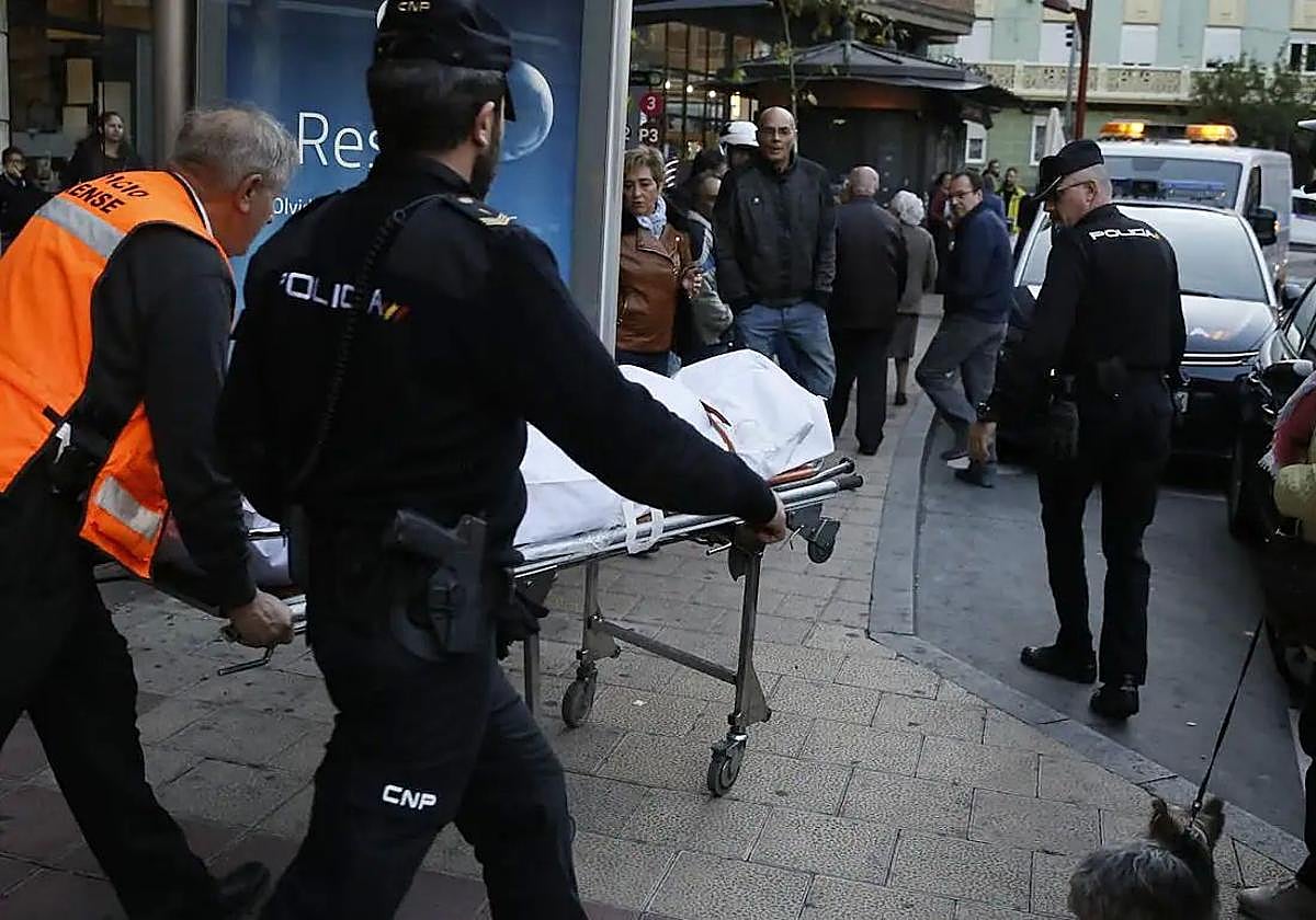 Los forenses trasladan el cadáver de la mujer asesinada en su piso de la Plaza Circular.