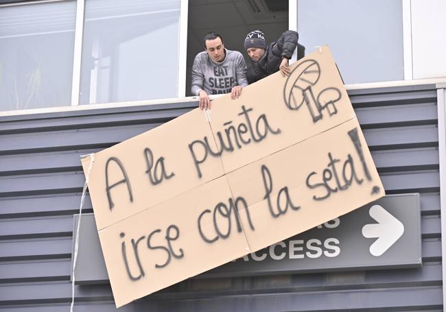 Dos trabajadores colocan un cartel reivindicativo en la fachada de Laumont Valladolid.