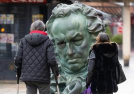 Dos personas observan una reproducción de la estatuilla de los Goya en la plaza del Carmen.