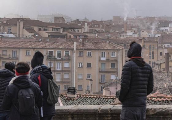 Varias personas observan el humo de las chimeneas en la ciudad de Segovia.