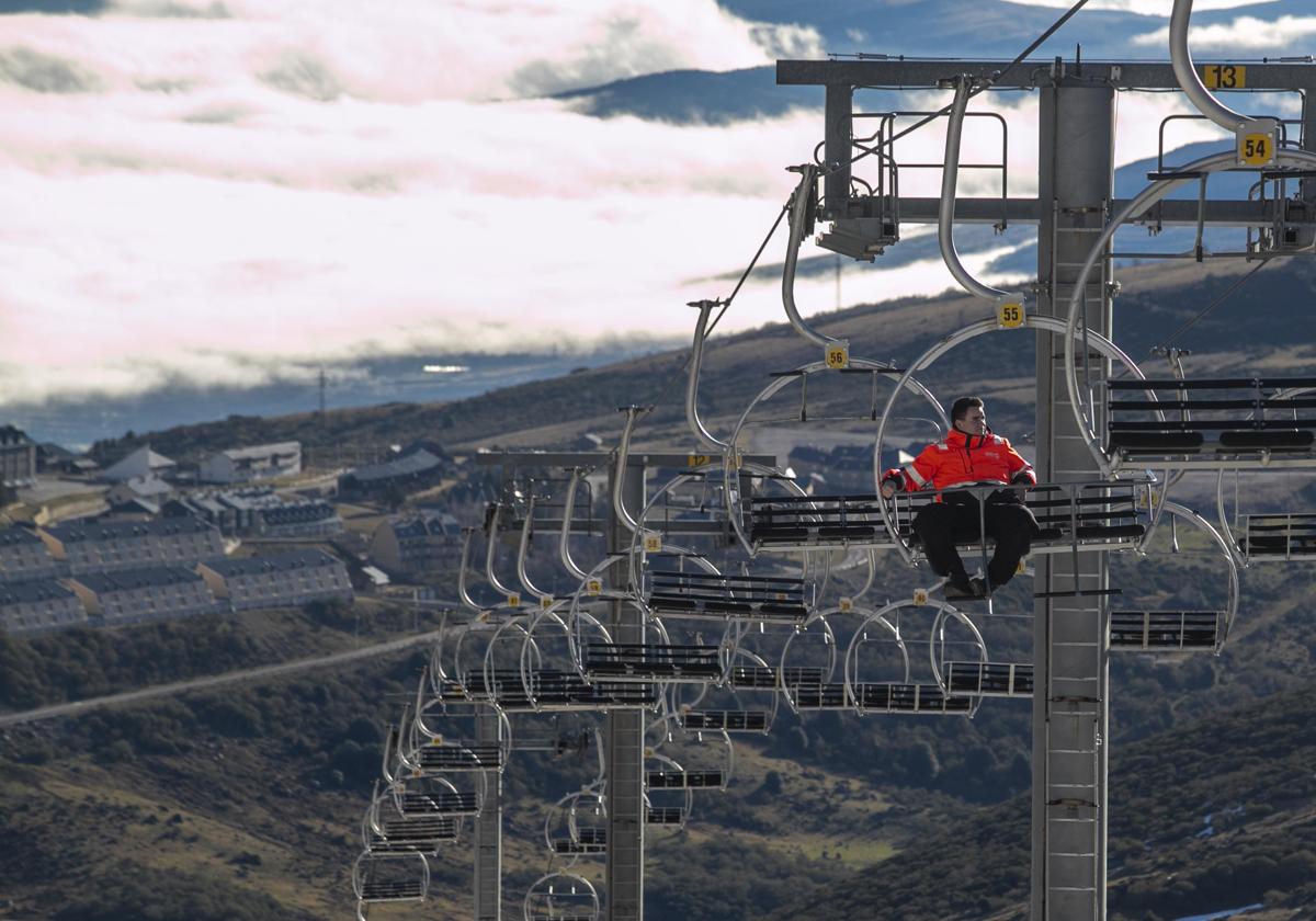 Un operario de Alto Campoo sube a la zona superior de la estación de esquí en el telesilla, sin apenas rastro de nieve en el horizonte, este mes de enero.