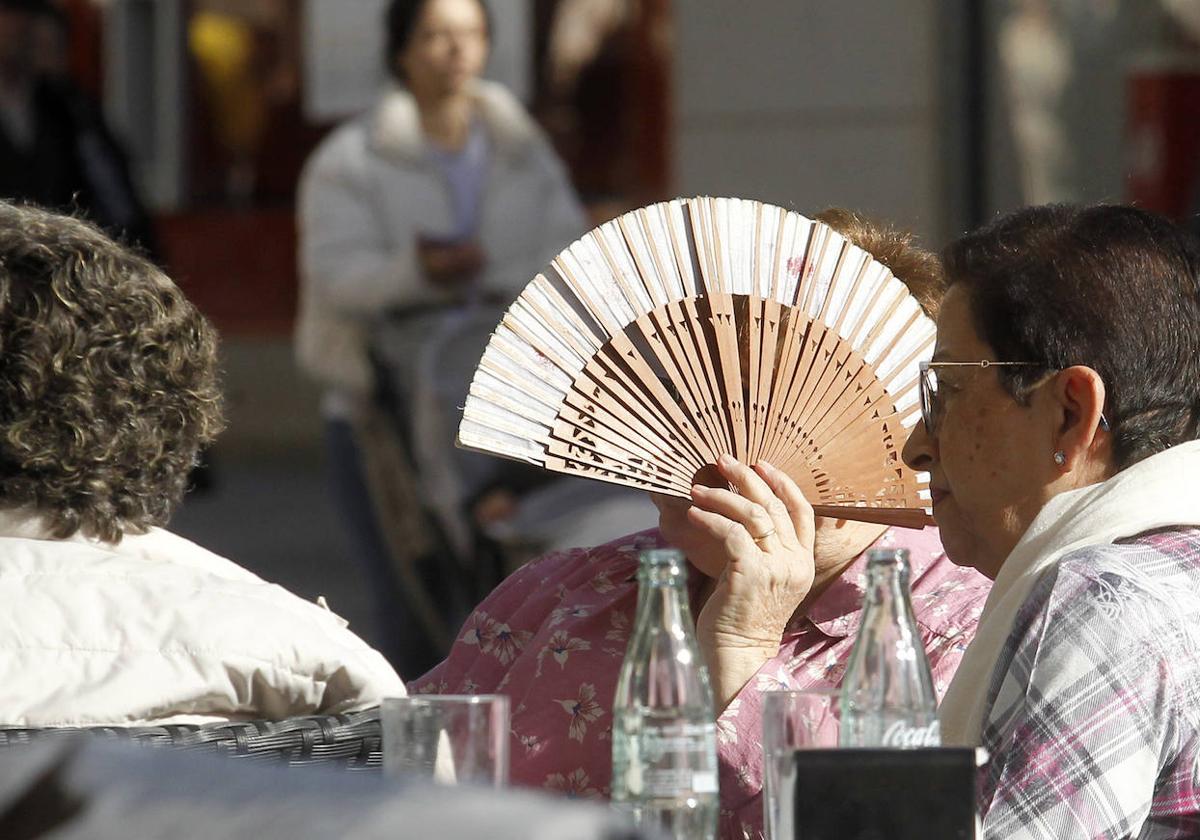 Una mujer se refugia del sol de enero con su abanico.