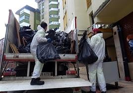 Los operarios retiran la basura acumulada en la vivienda de la calle Corpus Christi.