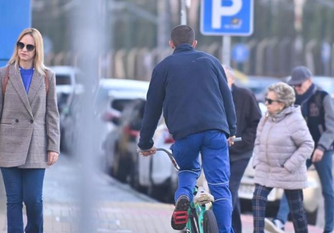 Una bicicleta circulando por la acera al lado de unos peatones.