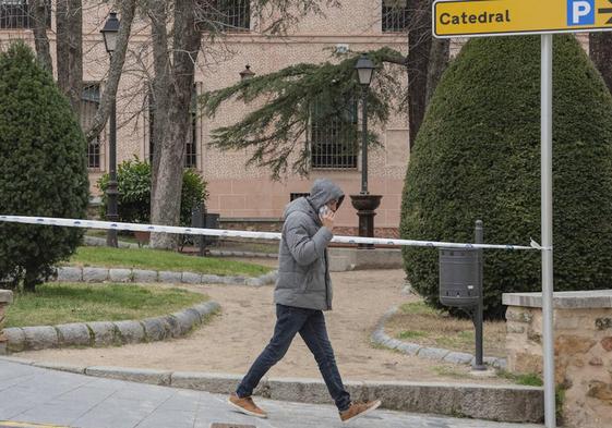 Un joven pasea junto a uno de los espacios verdes cerrados por el fuerte viento en Segovia este domingo.