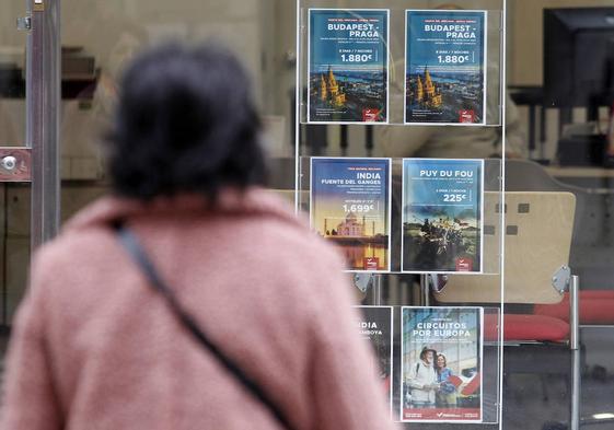 Una mujer observa los carteles de una agencia de viajes, con diferentes destinos por España y Europa.