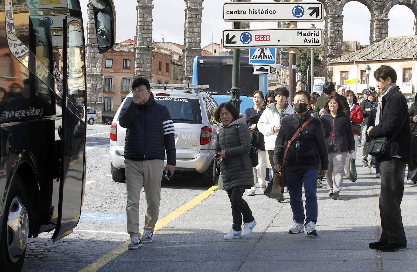 Un grupo de visitantes camina hacia un autobús turístico estacionado en Vía Roma.