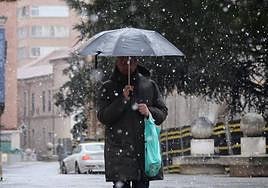 Un viandante se protege bajo un paraguas de la primera nevada del año en Valladolid.