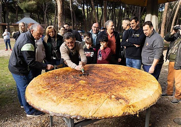 Jesús Martín parte la tortila de patata gigante en raciones.
