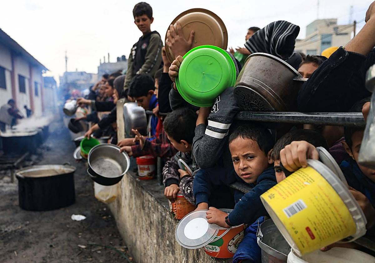Niños palestinos esperan para recoger alimentos en un campo de refugiados en Rafah.