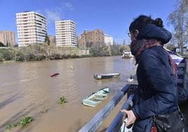 Una mujer observa la crecida del Pisuerga en Poniente, donde cubre sus paseos inferiores.