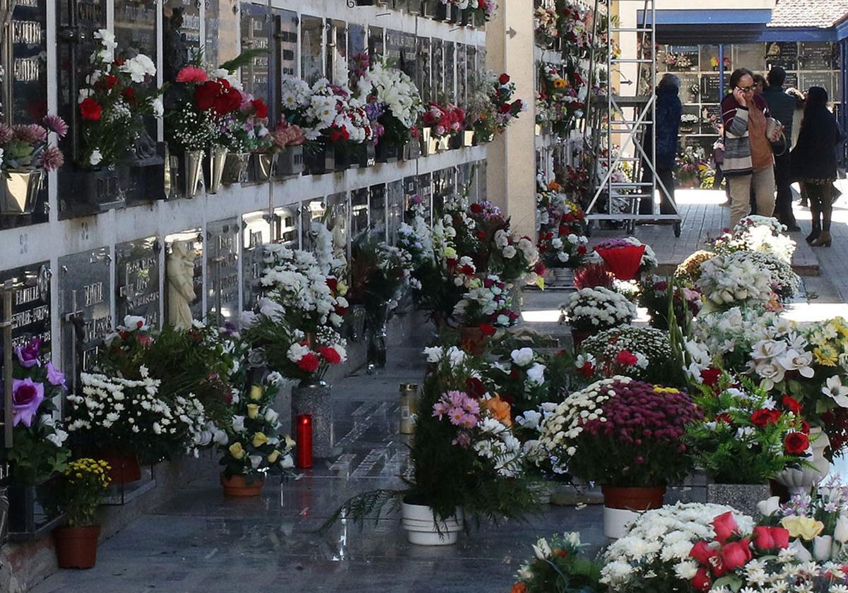 Flores y velas de llama colocadas en lápidas y nichos del cementerio de Segovia.