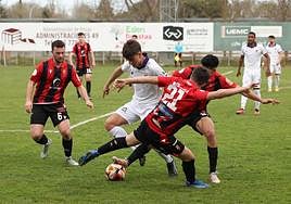 Adrián Calvo, jugador del Palencia CF, lucha por la posesión ante dos rivales del Laguna, este sábado.