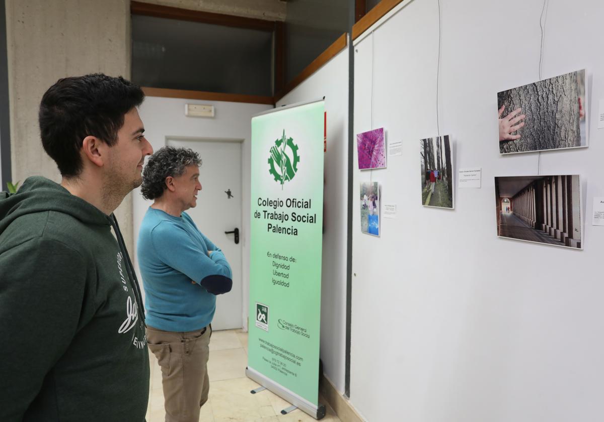 Dos personas observan la exposición de Trabajo Social en la Biblioteca Pública.