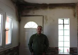 Andrés Fernández posa en el interior de la vivienda, llena de humedades.