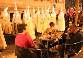 Una celebración de la procesión de la Buena Muerte al lado de terrazas llenas de gente.