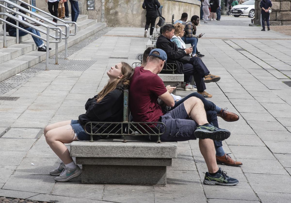 Dos jóvenes en pantalón corto toman el sol este jueves, en la plaza del Azoguejo.