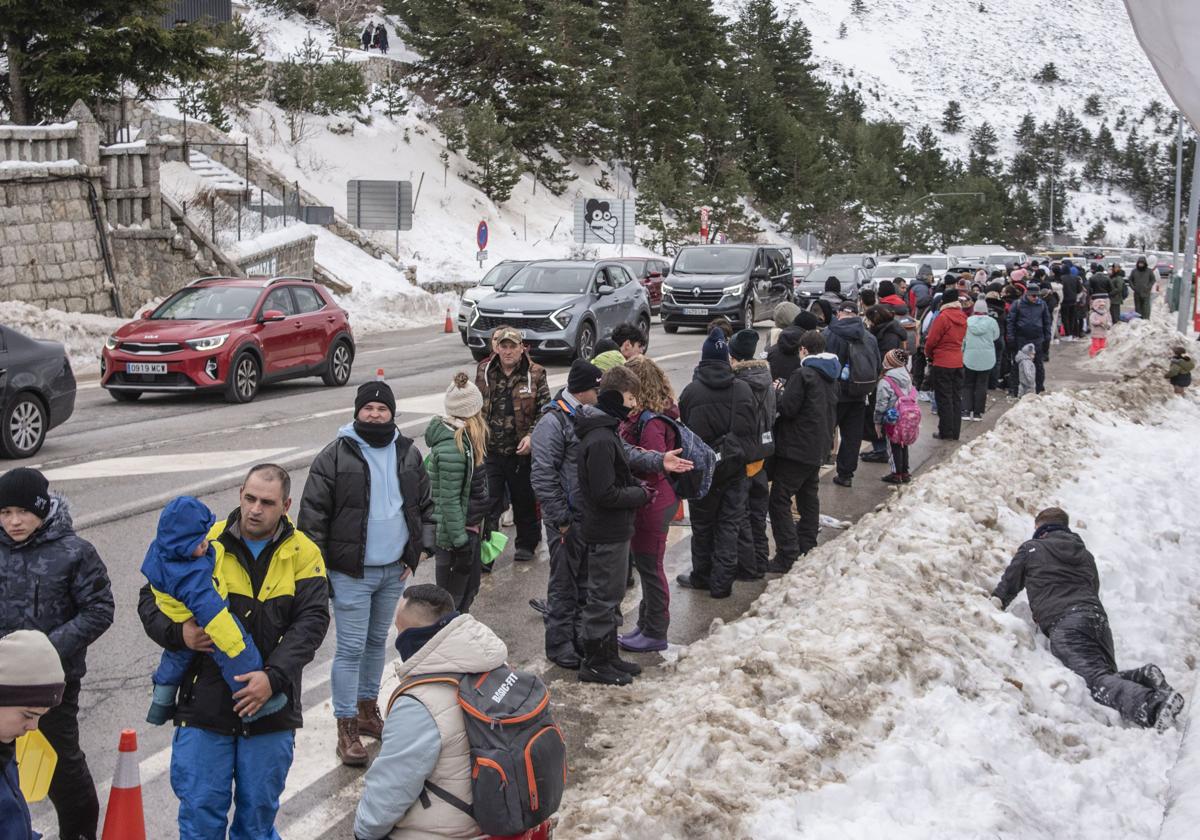 Personas transitan en el acceso a Navacerrada por el arcén junto al tráfico intenso de coches.