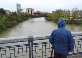 Un hombre observa el caudal del Pisuerga desde el puente de Juan de Austria.