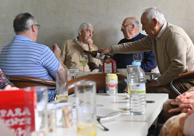 Daniel sirve un vino a sus vecinos Diego, Alejandro y Emilio en la hora del vermú en el local municipal