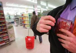Una persona esconde un paquete de embutido en un supermercado.